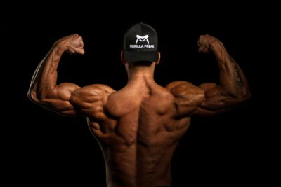 shoulder workout gym, bodybuilder athlete flexing his back muscles wearing gorilla freak cap