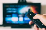 virtual habits that cut carbon footprint - hand holding remote to a TV screen