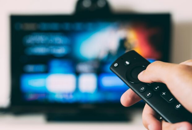 virtual habits that cut carbon footprint - hand holding remote to a TV screen