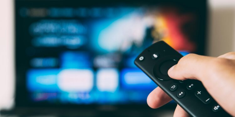 virtual habits that cut carbon footprint - hand holding remote to a TV screen