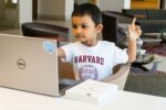 digital literacy in classrooms - child holding hand up in front of laptop