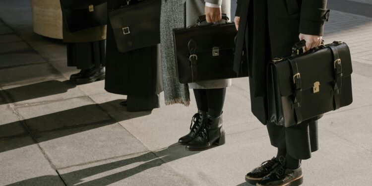 quiet luxury silhouttes, four people standing with briefcases and monochromatic outfits