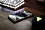 closeup photo of turned on smartphone near keyboard displaying twitch stream social apps chat stream