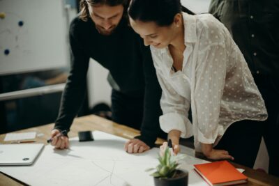 man and woman leaning on table staring at white board on top of table having a meeting for logo design