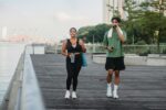 man and woman in black tank top and black leggings getting the benefits walking on wooden dock
