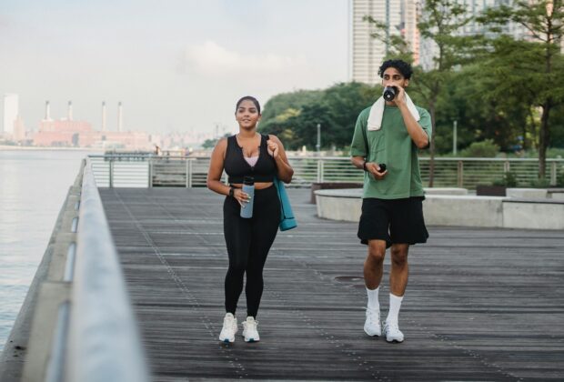 man and woman in black tank top and black leggings getting the benefits walking on wooden dock