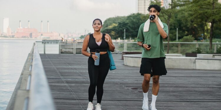 man and woman in black tank top and black leggings getting the benefits walking on wooden dock