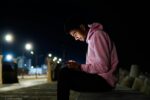a man sitting on a bench looking at his cell phone for digital stress relief activities