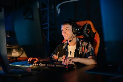 photo of a man playing on a computer and sitting on a gaming chair while smiling
