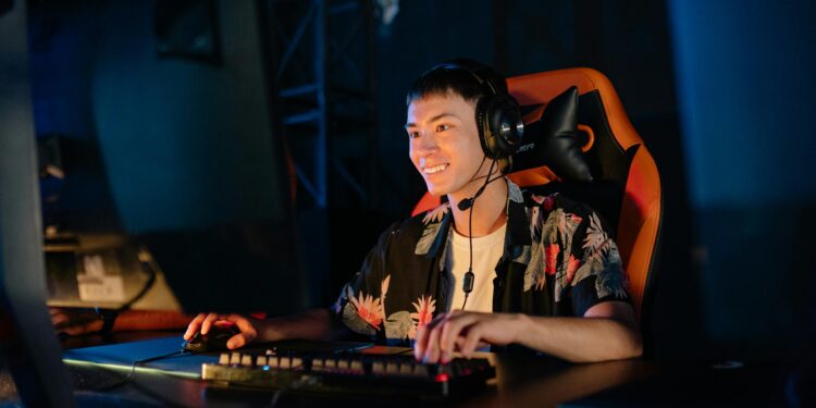 photo of a man playing on a computer and sitting on a gaming chair while smiling