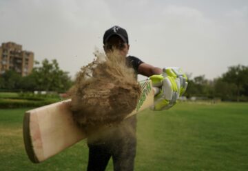 indian cricket player stricking a ball covered in mud