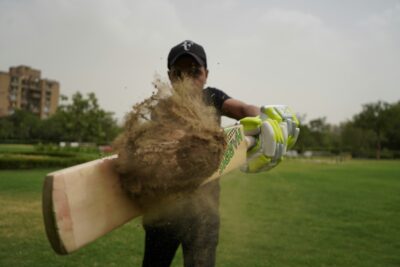 indian cricket player stricking a ball covered in mud