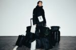 man surrounded by multiple black travel bags