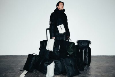 man surrounded by multiple black travel bags