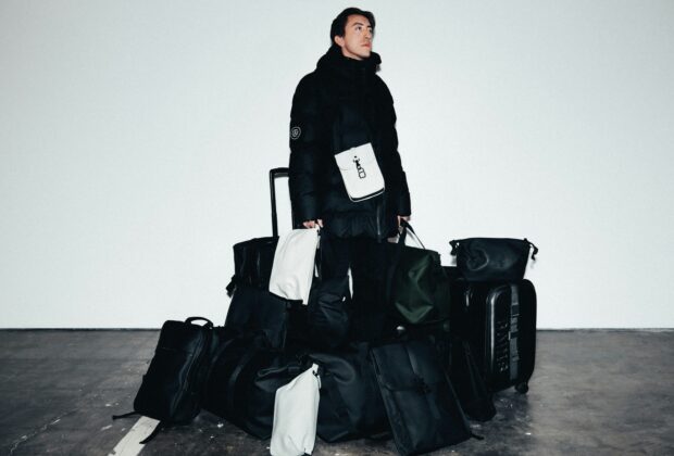 man surrounded by multiple black travel bags