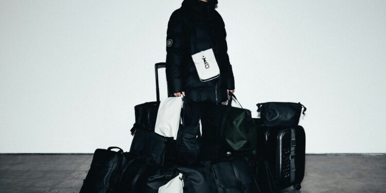 man surrounded by multiple black travel bags