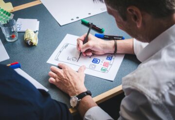 person drafting ux design on white paper