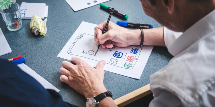 person drafting ux design on white paper