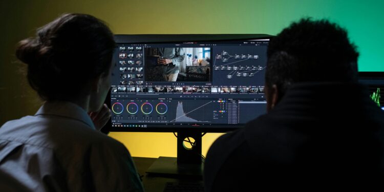 a man and a woman looking at a computer monitor and using a video editing app