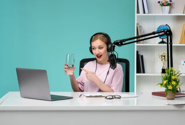 woman in front of laptop and mic holding a glass of water and recording one of the best podcasts for motivation